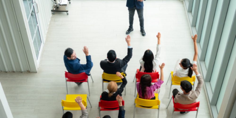 Top view of a group of business people sitting and listening to a presentation in a conference hall